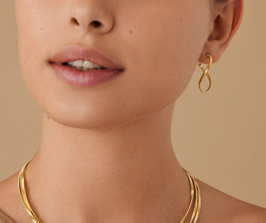 Subtle, elegant and full of finesse, these 18K yellow gold hoop earrings feature a striking twisted coil into an irregular infinity shaped hoop. Light and refined, they are a timeless classic, perfect for adding a touch of light to any outfit.