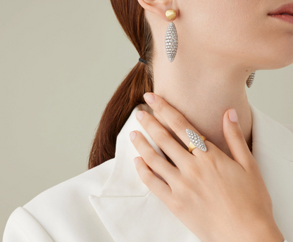 An 18K yellow gold ring full of volume, featuring a central oval shape pavé-set diamond element. The shank is finely hand-engraved using the ancient Florentine technique, which gives our gold a fine, brushed texture. That allows their powerful radiance to emanate