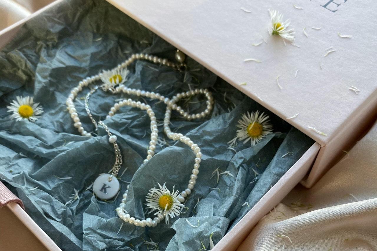 a jewelry gift box containing a pearl necklace and an initial pendant.