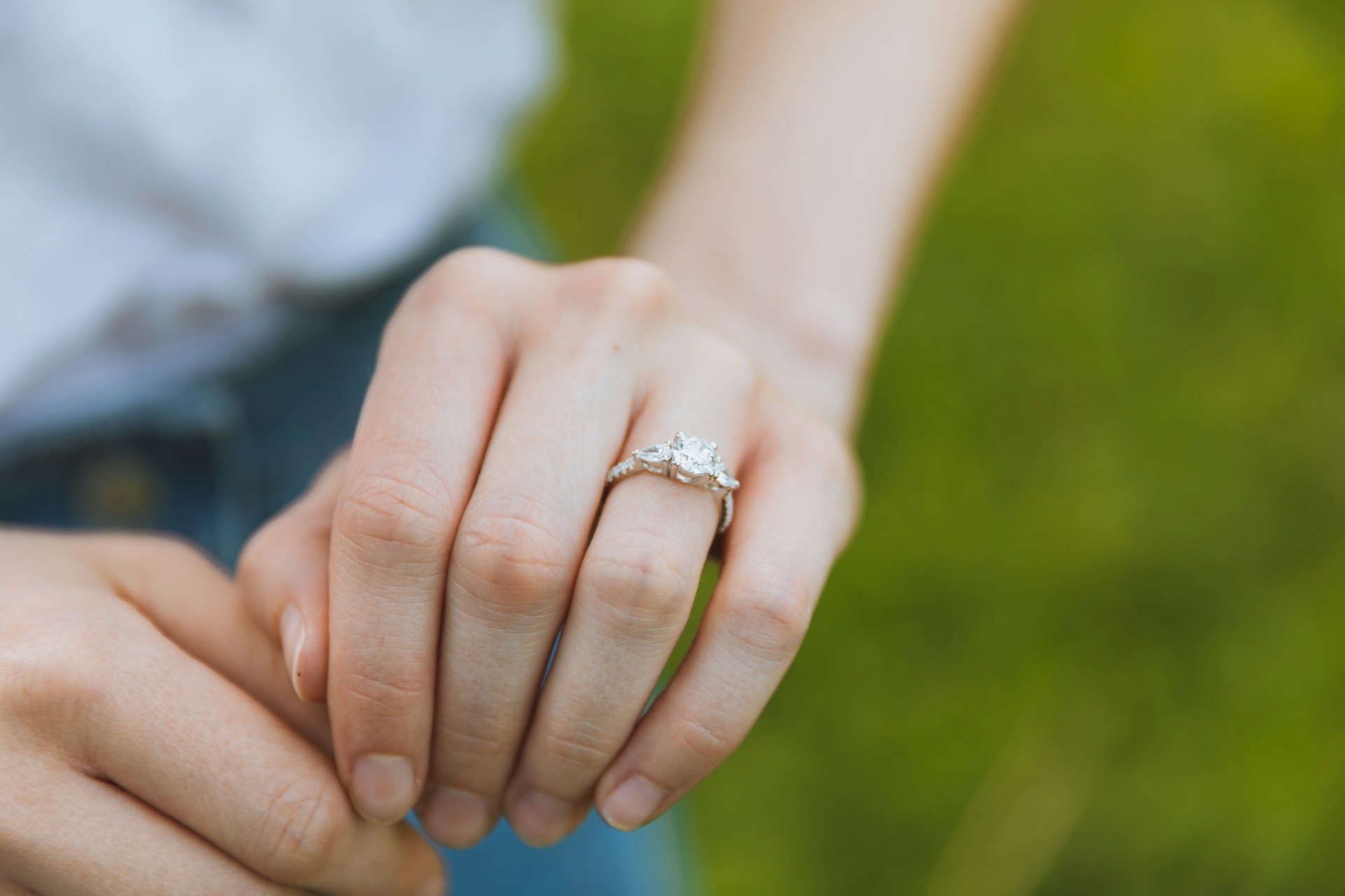 A close-up of a woman’s hand, with emphasis on her diamond engagement ring.