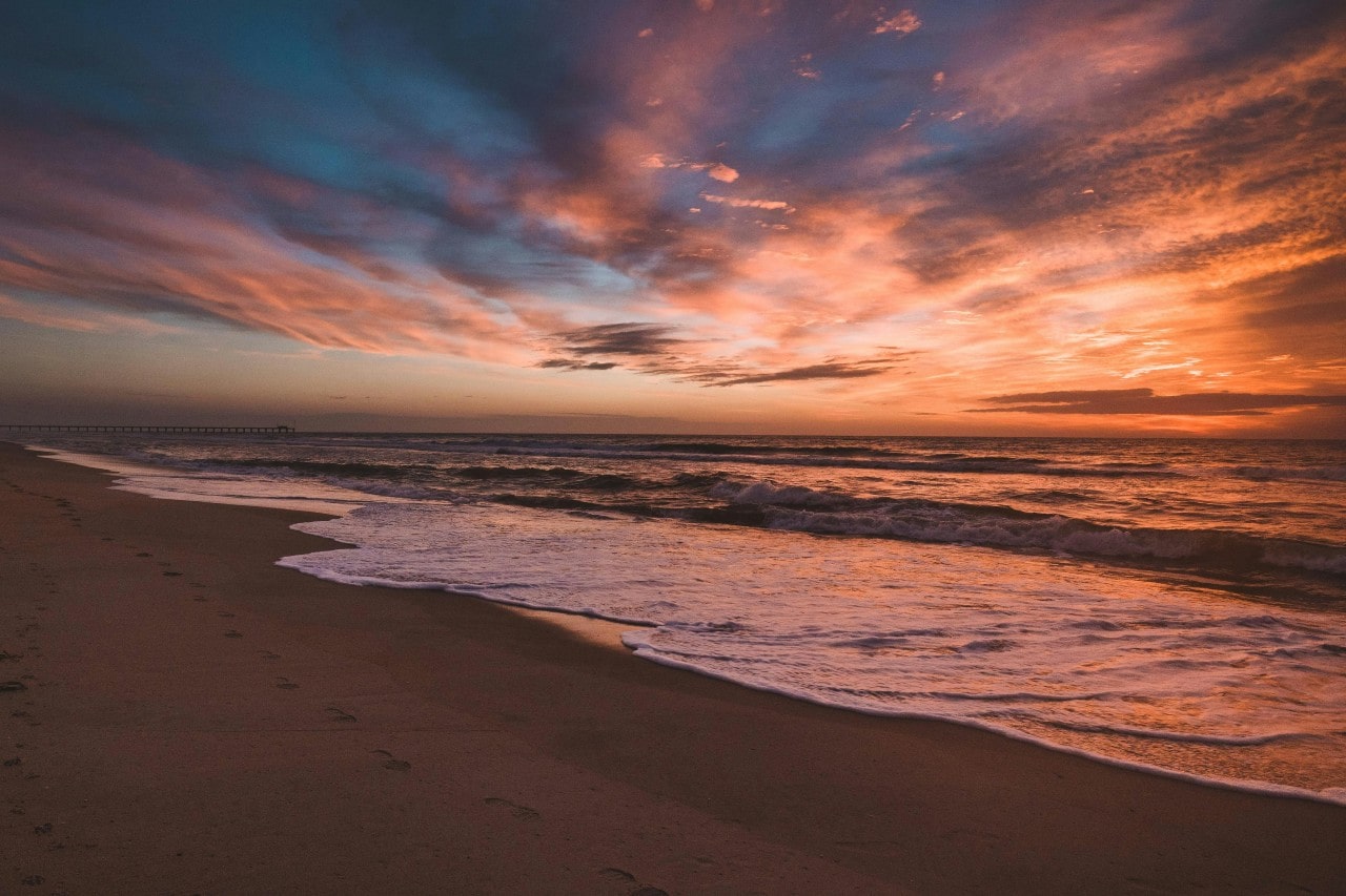 A beautiful beach at sunset, with footprints along the shore.