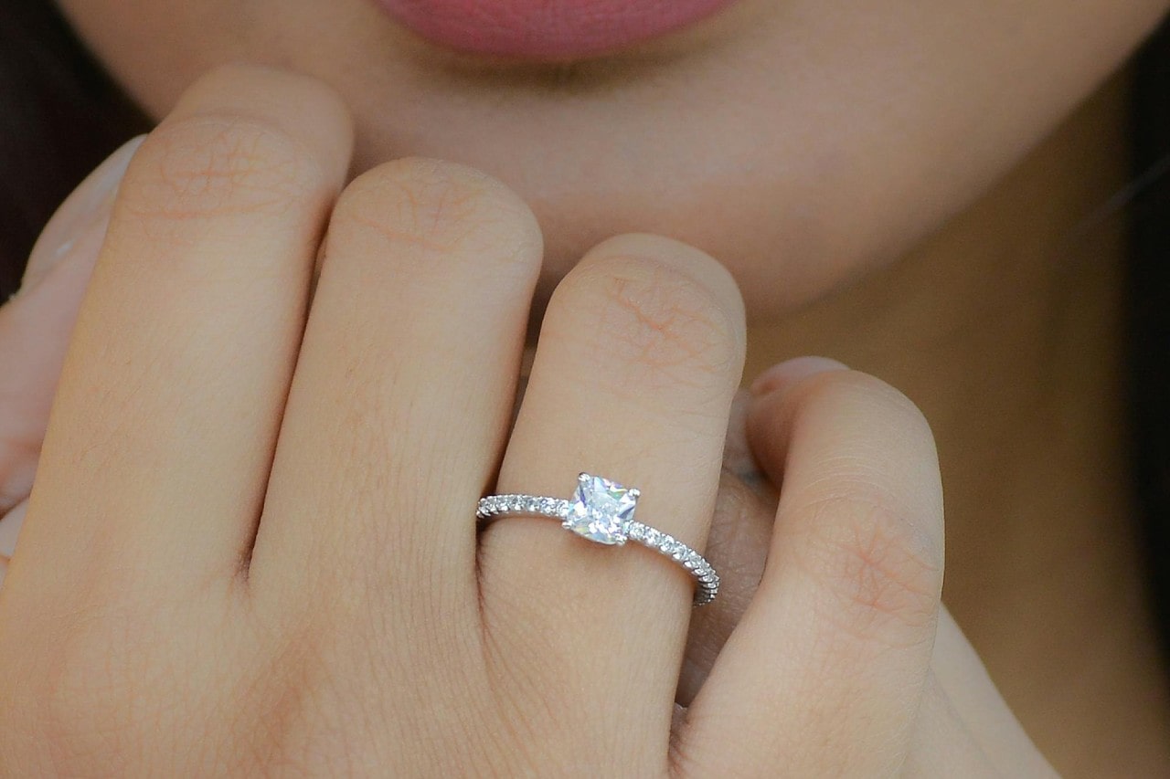 a woman’s hand wearing a white gold princess cut engagement ring
