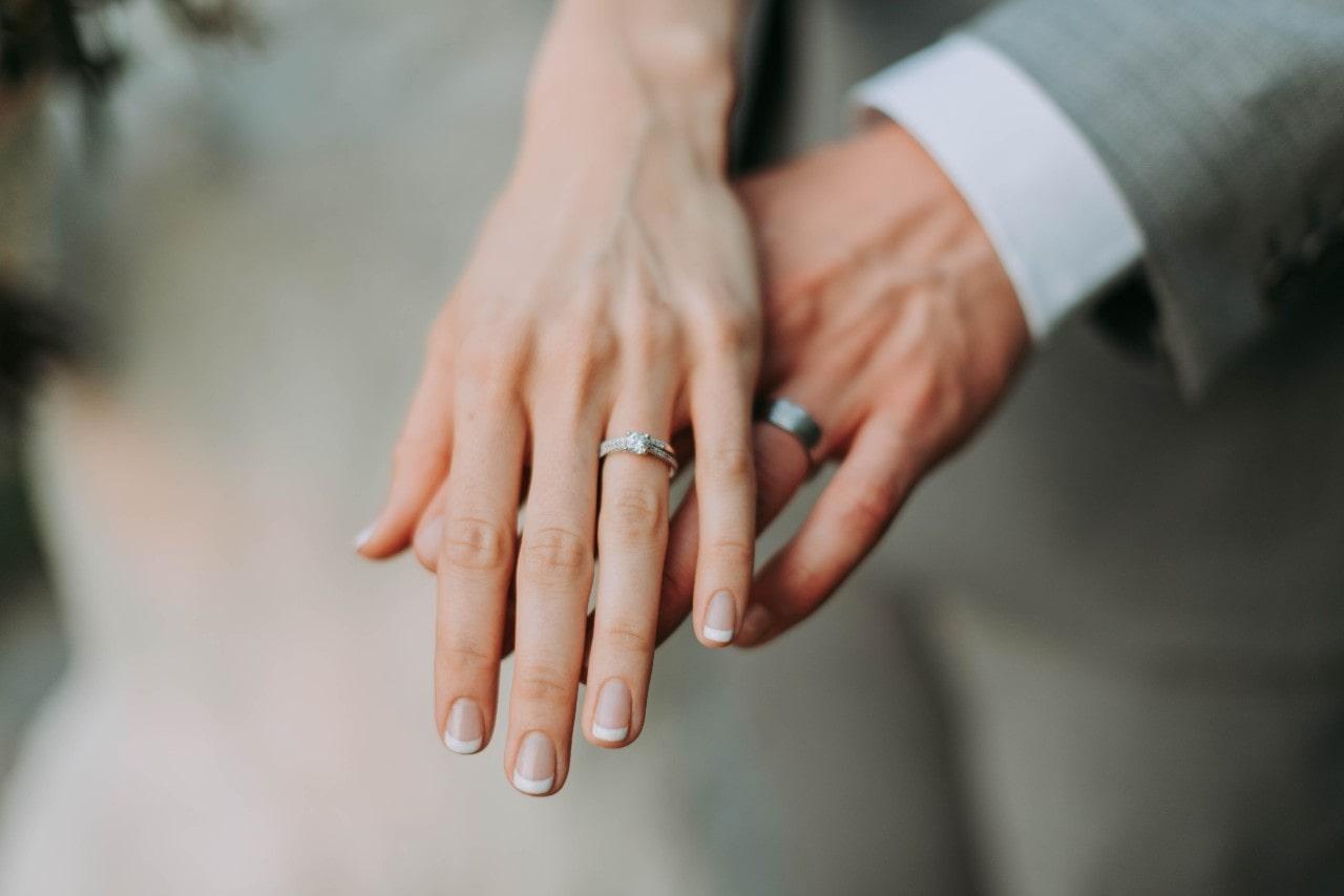 A couple showing their bridal rings as their hands touch