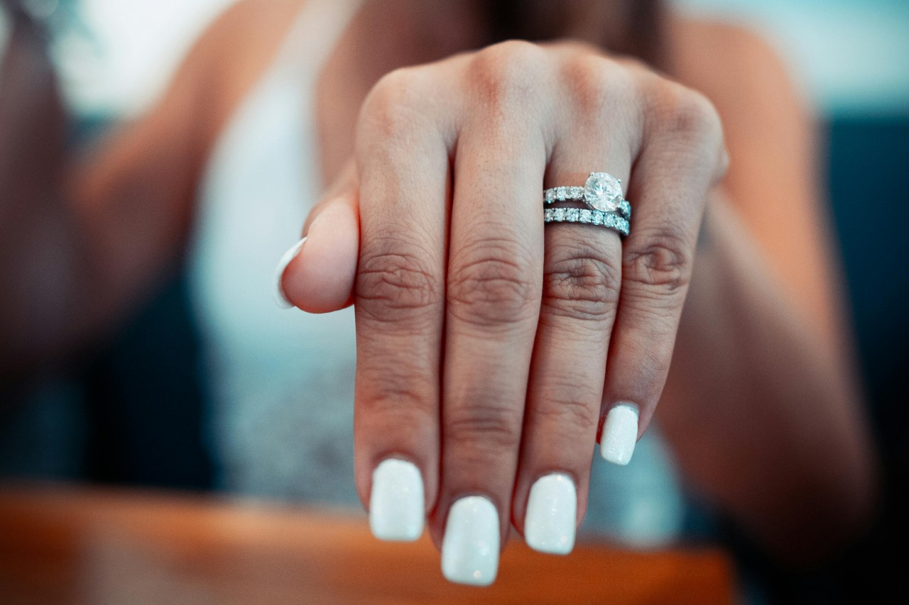 a woman’s extended hand adorned with a diamond engagement ring and wedding band.