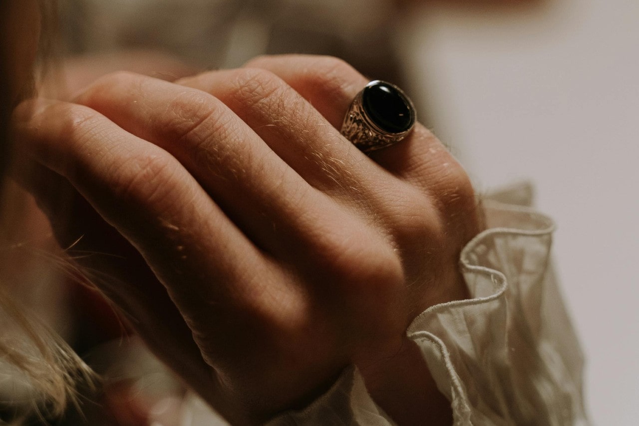 a woman’s hand adorned with a silver fashion ring with a black stone