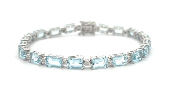 A white gold line bracelet featuring diamonds and emerald cut blue topaz, available at Weston Jewelers.