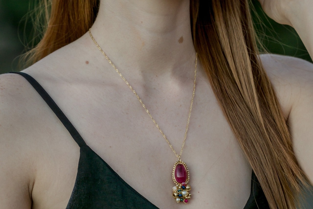 A yellow gold necklace with a cluster of gemstones as a pendant