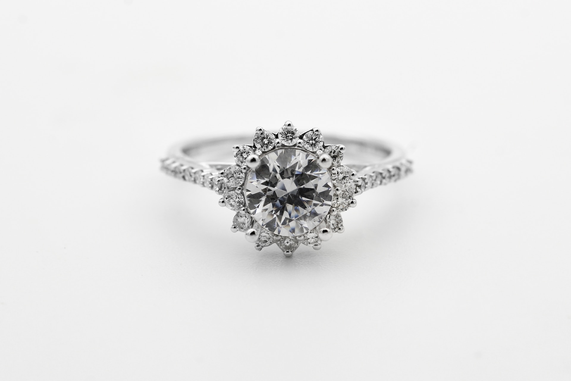 a platinum engagement ring with a floral inspired halo with side stones against a white background