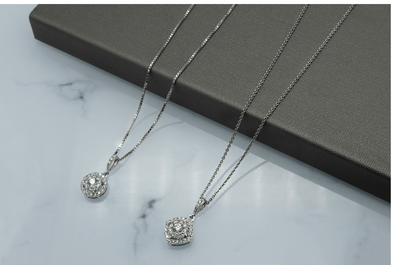 A close-up of two stunning white gold diamond pendant necklaces.